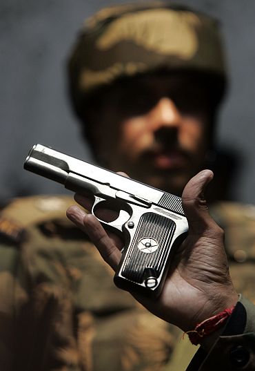 Indian army officer shows a seized pistol after a gun battle with Laskar militants to media in Kupwara, Kashmir