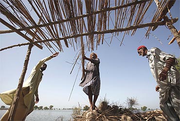 Villagers displaced by floods build a makeshift tent in Sindh province