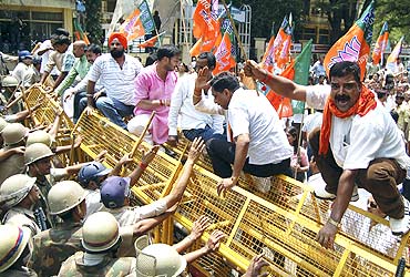 BJP activists shout slogans as police try to stop demonstrators during a protest against price hike in Lucknow