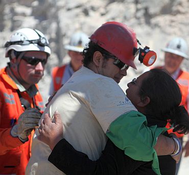 Trapped miner Daniel Herrera (red hard hat) hugs his wife after reaching the surface to become the 16th to be rescued from the San Jose mine in Copiapo