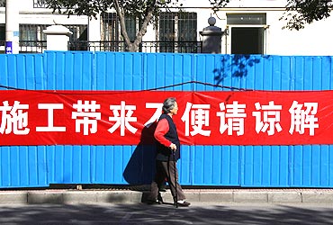 A woman walks past a banner reading, 'sorry for the inconvenience due to the construction' which is located at the entrance of a residential compound where Liu Xia, the wife of Chinese dissident and Nobel Peace Prize winner Liu Xiaobo, lives in Beijing