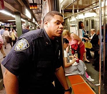 New York Police Department Officer Ariel Ortiz, left, looks into a train as he patrols the Times Square subway station in New York on Thursday