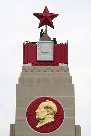 Workers at a monument with an emblem of Mao Zedong