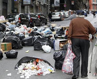A man walks on a street full of rubbish in Naples