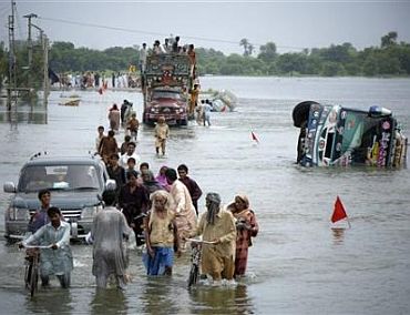 People wade through flood waters in Sindh