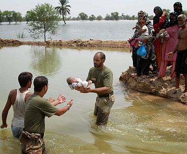 Pakistan army troopers transfer a baby to safety as others await their turn