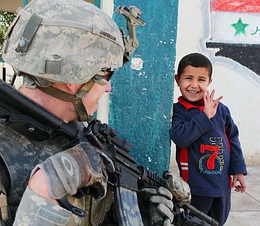 An Iraqi boy waves to a US soldier at the Al Tatawori school in Hor Albosch, Iraq