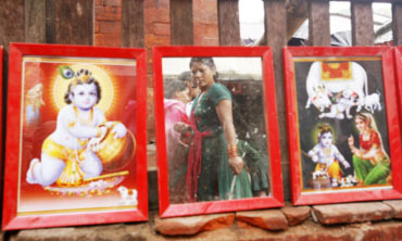A devotee is reflected in a mirror next to pictures of Lord Krishna