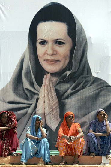 Women wait for Sonia Gandhi whose image looms large over them