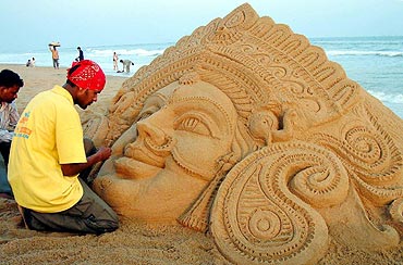 Patnaik, a sand artist, creates a sculpture of Goddess Durga in Puri