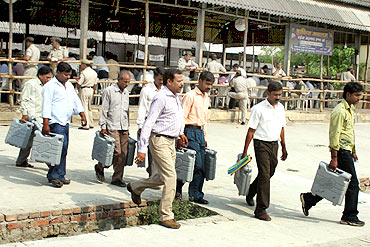 Election officials carry electronic voting machines for counting in Allahabad