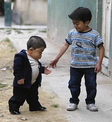 Hernandez walks with his eleven-year-old brother outside their home in Bogota