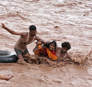 Rescuers help a woman to move a safer place from flooded Ghaghar river after heavy rains in Punchkula in Haryana