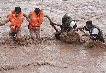 Rescuers help a woman to move a safer place from flooded Ghaghar river after heavy rains in Punchkula, Haryana