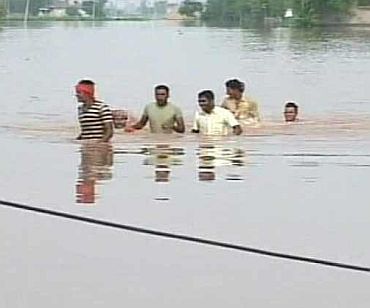 People wade through neck-deep flood waters