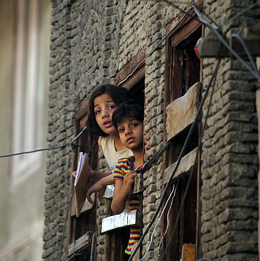 Children look out of a window of their home during a curfew in Srinagar