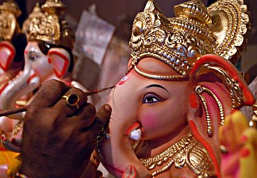 An artist gives finishing touches to a Ganesha idol