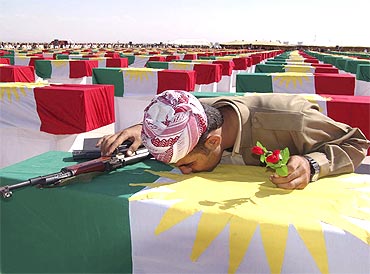 A Kurdish Peshmerga soldier kisses the coffin of a person killed during former Iraqi President Saddam Hussein's rule at a ceremony in Arbil's airport, northern Iraq, on October 17, 2005