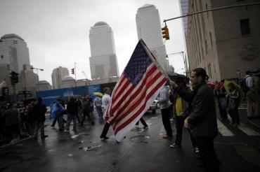 A man holds a US flag while others pause for a moment of silence