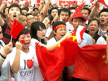 People shout slogans praising China during a flag-raising ceremony at Tiananmen Square in Beijing