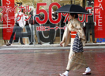 A woman walks past a shop holding a bargain sale at a shopping district in Tokyo