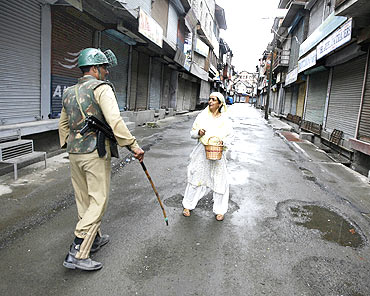 A policeman stops a woman during a curfew in Srinagar