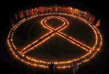 Students hold oil lamps beside a symbol of AIDS to mark the World AIDS Day in Chennai