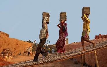 A woman joins her two male co-workers at a brick kiln