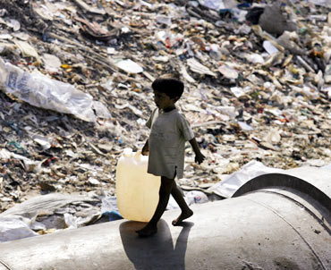 A boy walks past a garbage dump in Mumbai