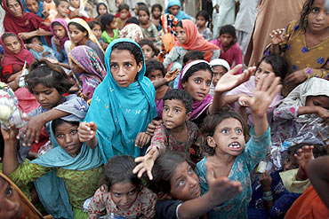 Flood victims stretch their hands towards aid workers distributing gifts in Pakistan's Punjab