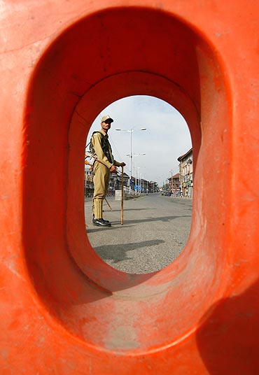 A policeman stands guard on a deserted road during a curfew in Srinagar
