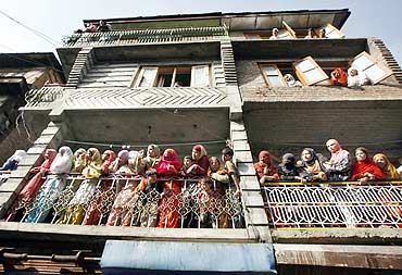 Women watch the funeral procession of a Kashmiri youth who was killed during an anti-India protest