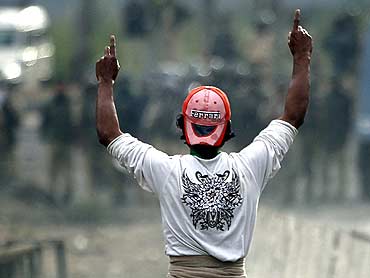A Kashmiri protester gestures towards policemen during an anti-India protest in Srinagar