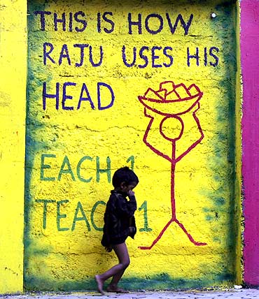 A child walks past graffiti on a street side wall in Mumbai