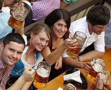 People wearing traditional Bavarian clothes toast with beer during the opening day of the 177th Oktoberfest in Munich