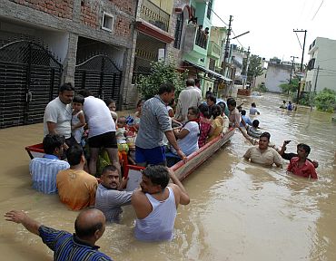 Residents travel by boat on a flooded street after heavy monsoon rains in Moradabad