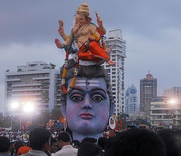 Devotees watch idols of Ganesha and Lord Shiva as they are placed on the seashore before immersion
