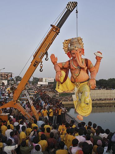 A crane lowers a Ganesh idol for immersion in river Sabarmati