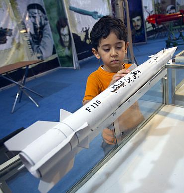 A boy looks at a model of an Iranian third-generation Fateh-110 (Conqueror) surface-to-surface missile while visiting a war exhibition held by Iran's Basij militia and revolutionary guard to mark the anniversary of the Iran-Iraq war (1980-88) on September 23