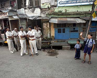 Schoolchildren wait for their school bus as policemen stand guard in Ayodhya