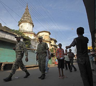 Boys fly a kite as paramilitary soldiers patrol a road in Ayodhya