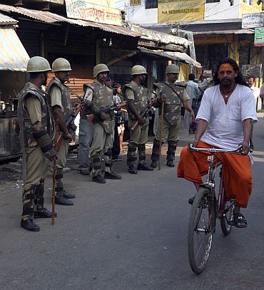 A priest cycles past paramilitary troopers guarding a road in Ayodhya