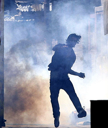 A protestor throws stones at policemen