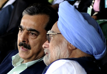 PM Singh speaks with Pakistan PM Gilani as they watch the match