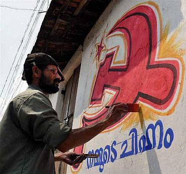 A worker gives finishing touches to a party banner on a wall