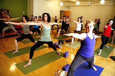 Yoga students hold a pose during an afternoon class at a yoga studio in New York