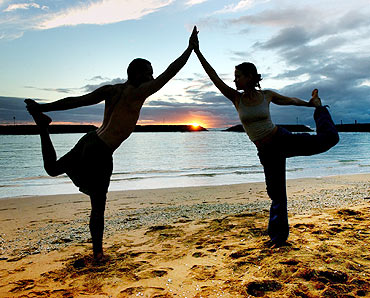 A couple practises yoga on Magic Island in Ala Moana Beach Park in Honolulu, Hawaii