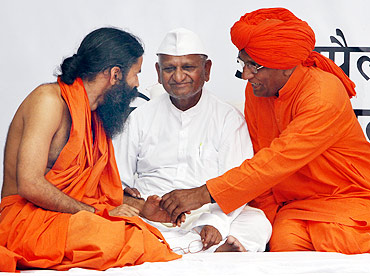 Yoga guru Swami Ramdev speaks with social activist Swami Agnivesh as Anna Hazare