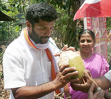 K T Benny, a first time candidate with no political lineage, sips coconut water offered by locals in Chalakudy