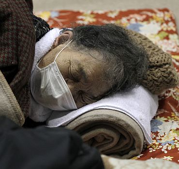 An evacuee closes her eyes at an evacuation centre set in a gymnasium in Yamagata, northern Japan